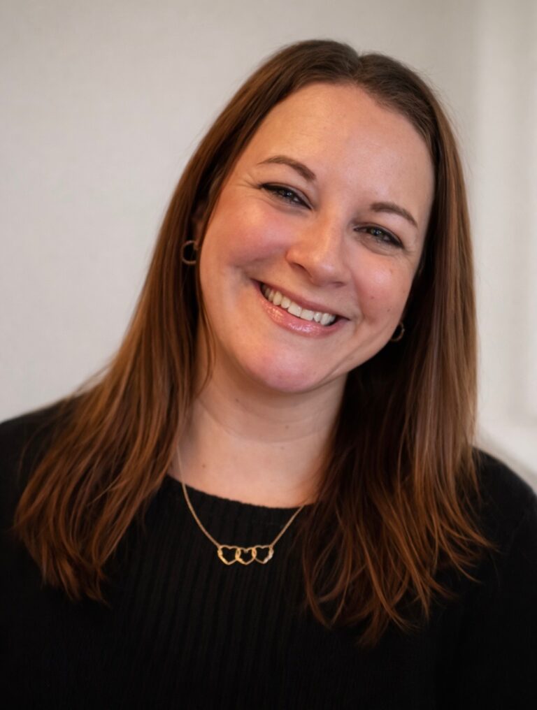 Smiling woman with long brown hair wearing a black top.